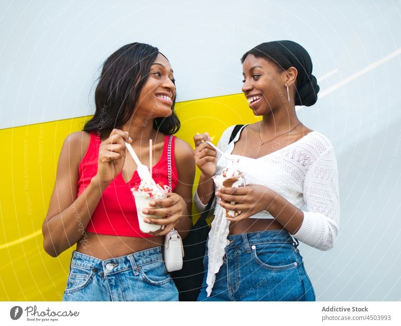 Cheerful black women eating ice creams friendship dessert sweet treat bonding street pastime indulge spare time female african american lifestyle spend time