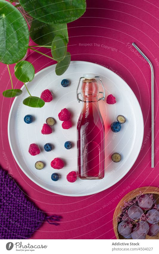 Bottle of fruit juice on plate bottle berry sweet serve drink beverage refreshment vitamin glass delicious tasty healthy appetizing assorted mix raspberry