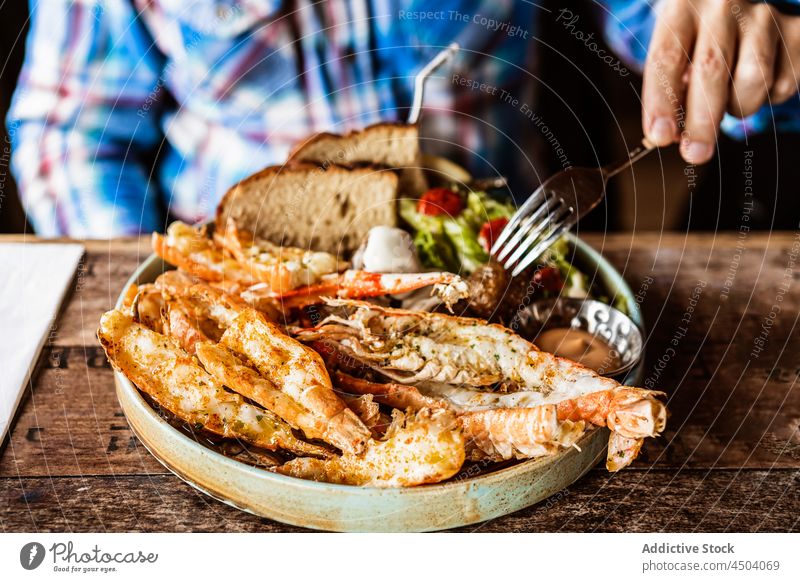 Man eating grilled king prawns with bread and salad man restaurant dish fork food seafood tasty male delicious iceland table hand plate meal yummy shrimp dinner