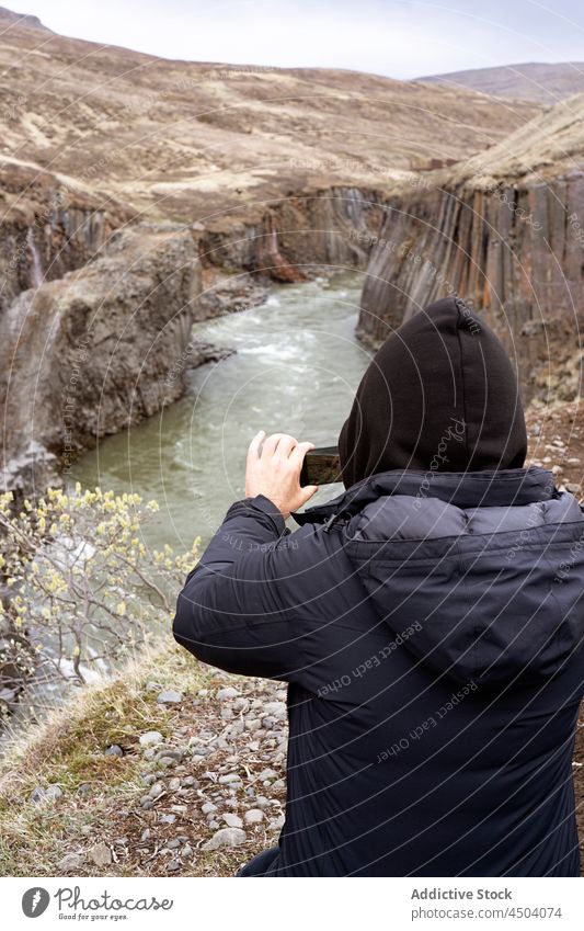 Traveler taking photo of picturesque scenery of canyon in daylight person travel take photo smartphone gadget cliff nature landscape river traveler iceland