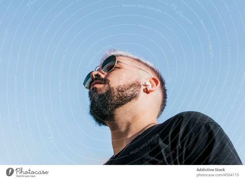 Bearded guy in sunglasses against cloudless blue sky man calm pensive thoughtful individuality trendy appearance personality male mustache sunlight casual beard