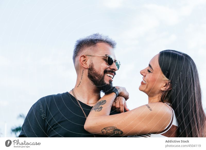 Happy couple hugging and laughing on street cheerful embrace happy sunglasses positive fun man woman girlfriend boyfriend relationship daytime casual smile