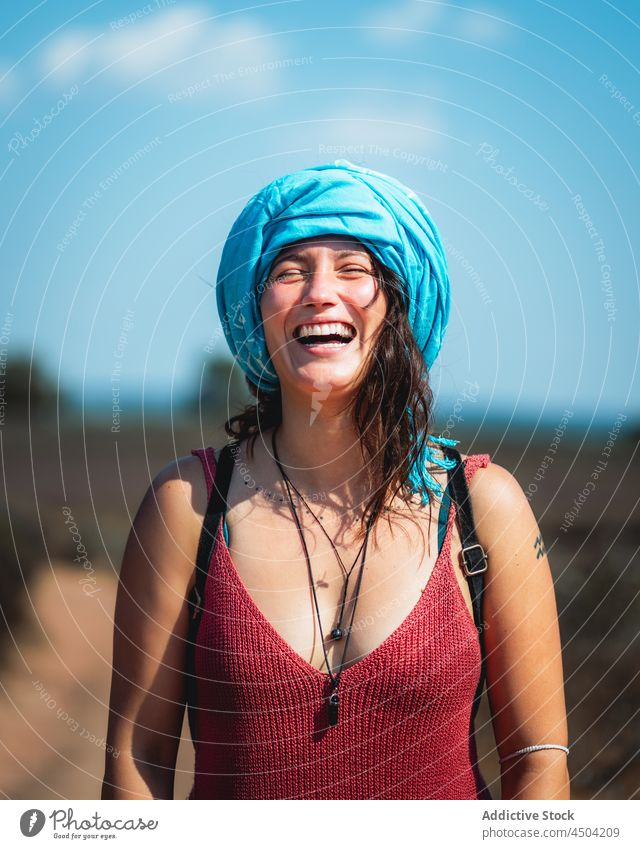 Cheerful woman with headscarf standing in nature in sunny day positive laugh countryside optimist cheerful glad happy delight female brown hair casual daytime