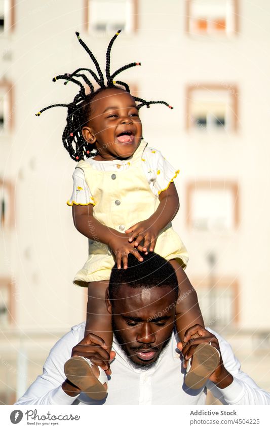 Happy black father jumping with daughter on shoulders on street man girl fun kid fatherhood parent cheerful female african american child happy urban bonding