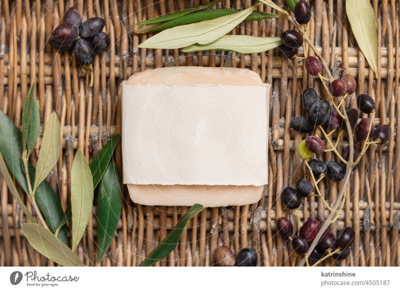 Soap bar on a wattled table with olive branches mockup Handmade soap blank top view paper wooden beige webbed concept white gift idea zero waste mediterranean