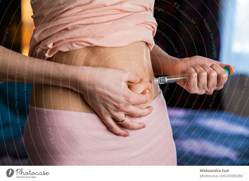 Woman making hormonal therapy injection into her belly. Close up syringe pen. Person in bedroom, in vitro fertilisation treatment. diabetes fertilization
