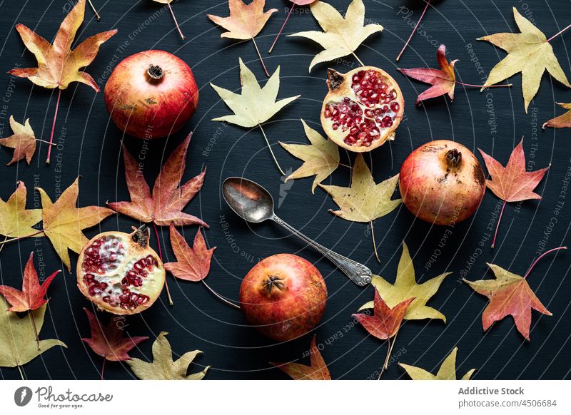Dried autumn leaves with pomegranate on plates fruit composition slice scatter dried halved ripe tasty delicious healthy season leaf sweet vitamin food berry