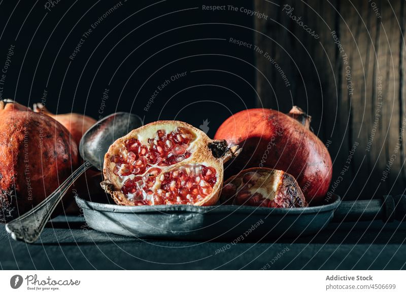 Ripe pomegranate on pan on table ripe fruit vitamin healthy food half seed chop kitchen tablecloth crumple whole tasty piece cut halved red slice creased grain