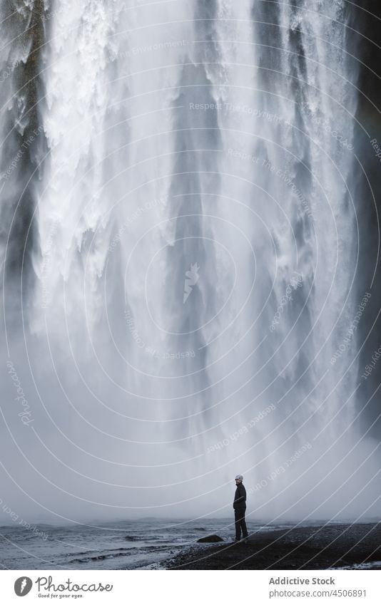 Male traveler standing under picturesque waterfall man admire river nature cliff landscape stream spectacular hiker male casual rocky riverside explore gorge