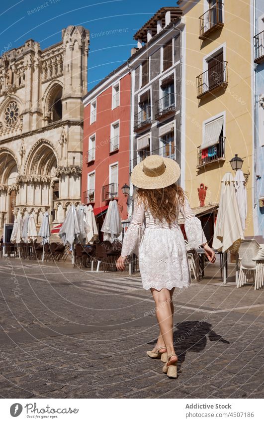 Back view of woman walking on street old city pleasure trip expressive female optimist glad pavement building satisfied carefree long hair positive sunshine