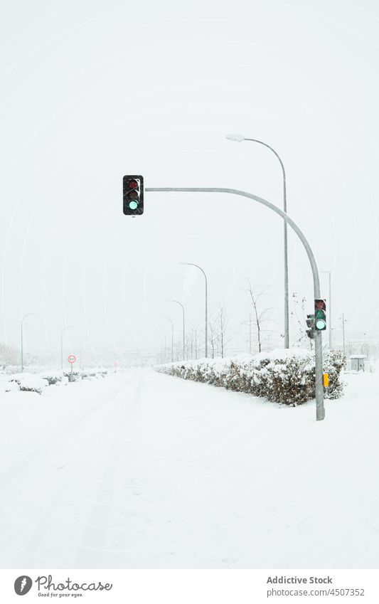 Green traffic light on snowy road green rule signal control winter post attention glow regulation warning signage cold overcast illuminate pole cloud spain