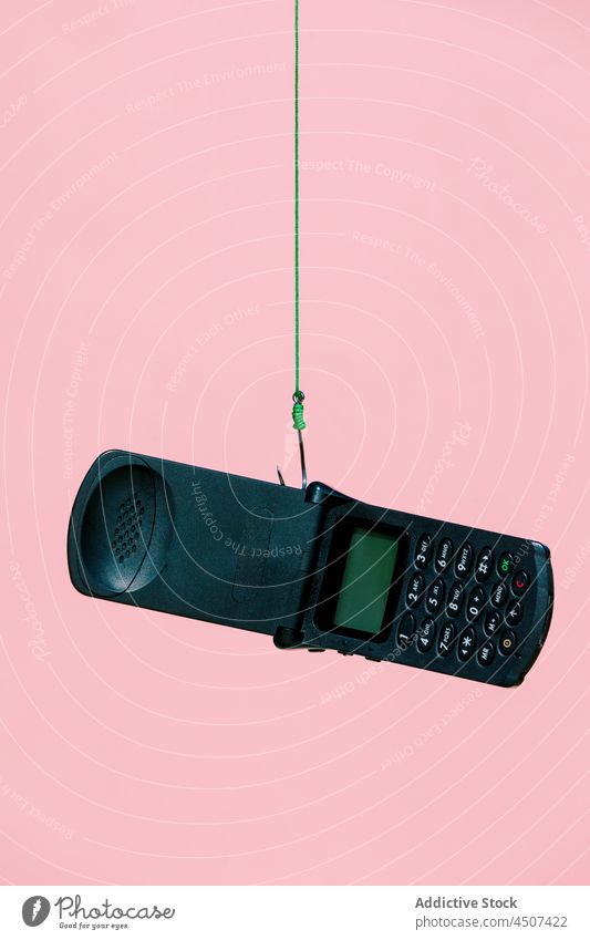Old fashioned flip mobile hanging on hook phone old fashioned obsolete used rope concept device black style discontinued vivid studio color nostalgia retro