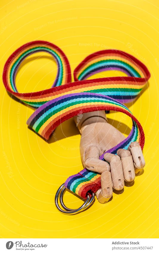 Multicolored strap in mannequin hand concept artificial accessory design style rainbow ring creative light colorful vivid metal bright studio trendy long