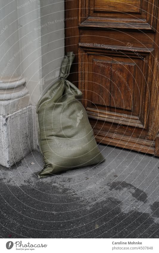 Green sandbag stands in front of a front door as protection against floods Sandbag Flood Environment Old Entrance House (Residential Structure) Building Facade