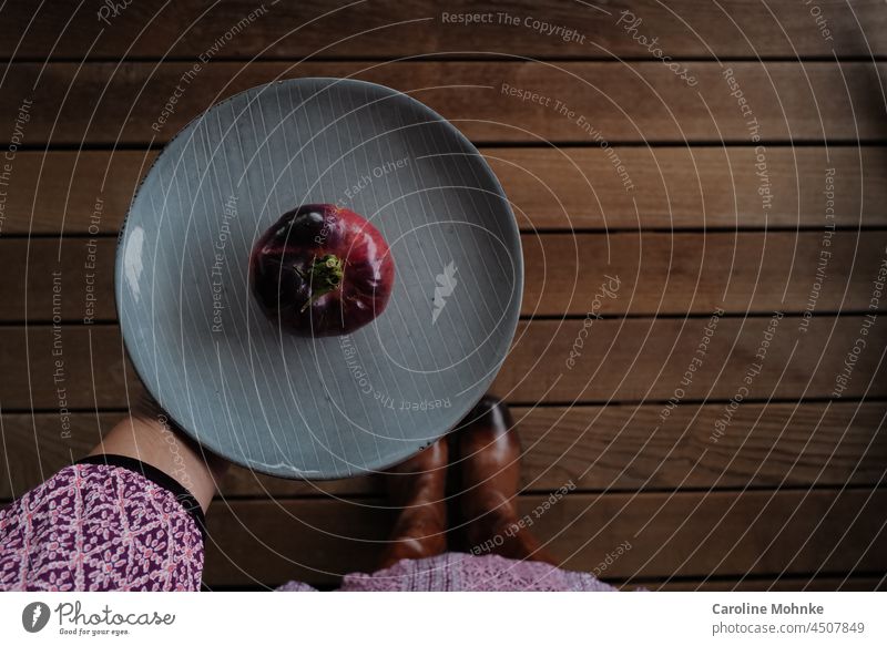 Eye catcher woman holding light blue plate with a black and red tomato Eating Food Nutrition Vegetarian diet Organic produce Colour photo Healthy Eating