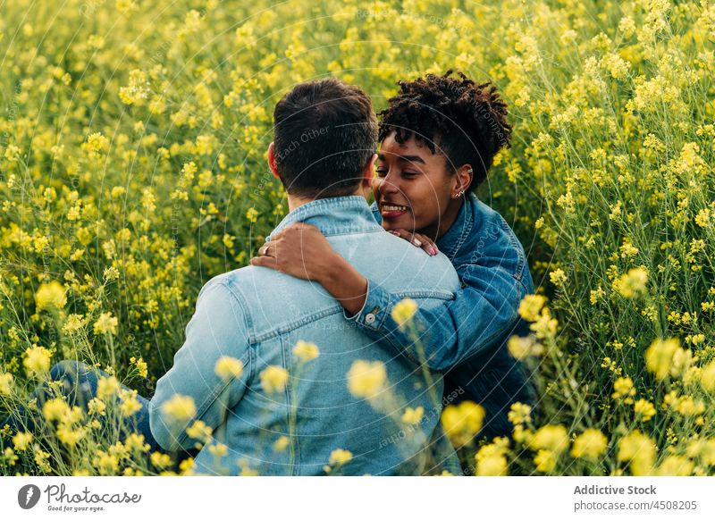 Happy young diverse couple looking at each other in meadow in sunlight date romantic love together relationship affection nature multiracial multiethnic