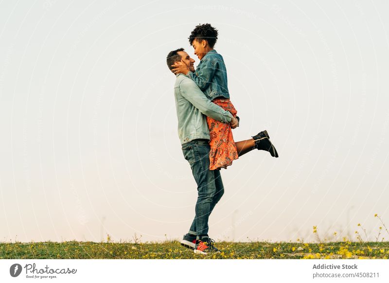 Enamored happy diverse couple embracing on grassy meadow embrace love smile relationship romantic sunset together nature hug countryside affection boyfriend