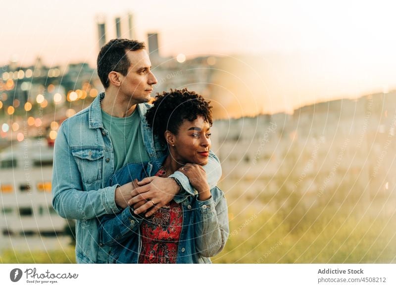 Loving dreamy diverse couple cuddling and looking away on street cuddle love relationship spend time romantic date together sunset city hug boyfriend girlfriend