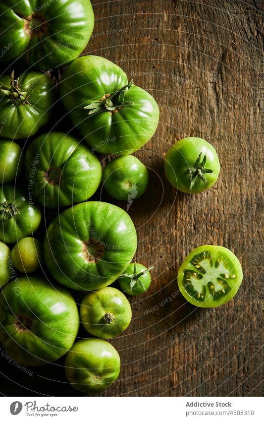 Slice tomato on a wooden table near of unripe tomatoes cherry tomato scatter slice vegetable harvest vitamin many countryside agriculture agronomy garden farm
