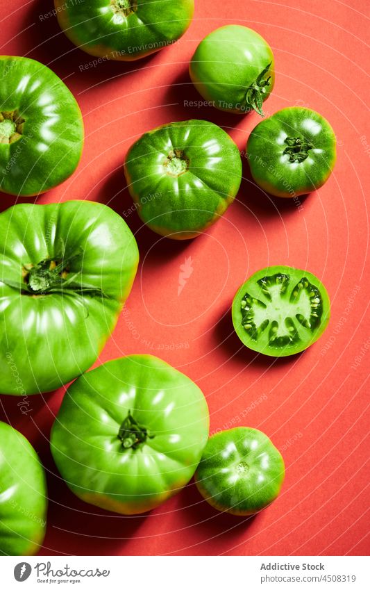 Green tomatoes scattered on bright red background green unripe agriculture slice harvest agronomy farm solanum lycopersicum vitamin food vibrant concept
