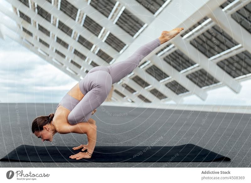 Flexible woman doing flying lizard asana yoga solar panel exercise training street balance practice energy female flexible workout modern sportswear wellness