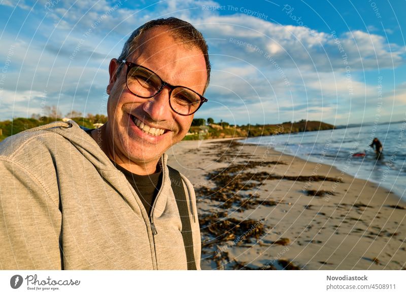 Middle age man wearing glasses smiling happy on the beach, autumn's day Man Middle-aged Caucasian caucasian ethnicity 40s 40-45 years Smiling Beach