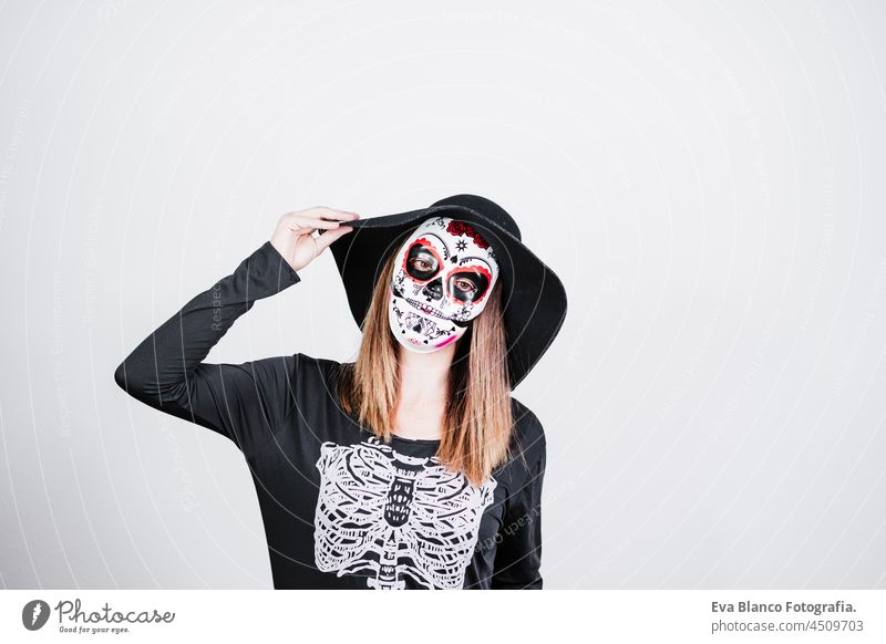 woman wearing mexican face mask during halloween celebration. skeleton costume and black stylish hat. Halloween party concept traditional flower death scarey