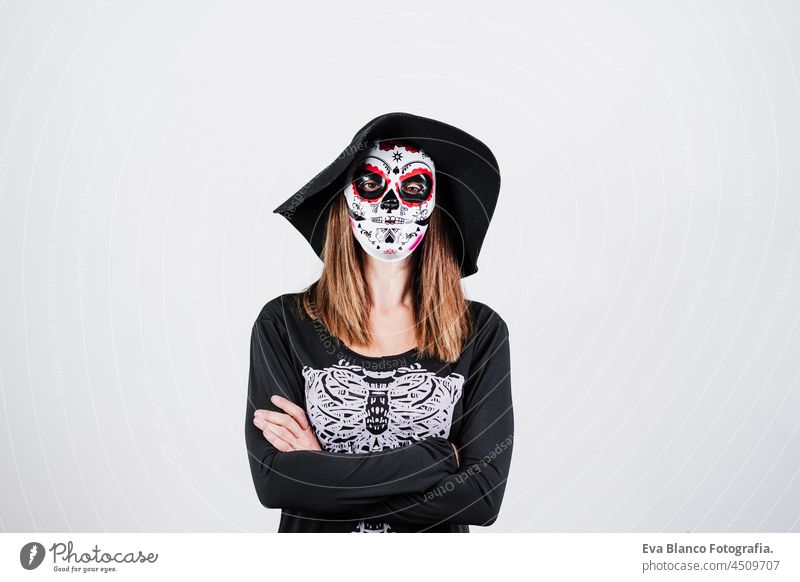 woman wearing mexican face mask during halloween celebration. skeleton costume and black stylish hat. woman with arms crossed. Halloween party concept