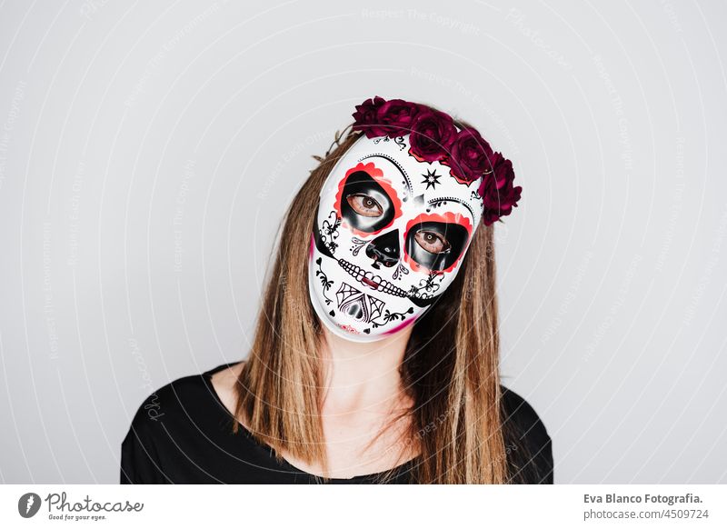 woman wearing mexican face mask during halloween celebration. woman wearing skeleton costume and red roses diadem on head. Halloween party concept traditional
