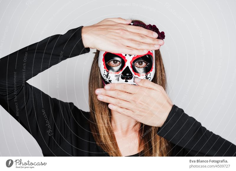 woman wearing mexican face mask during halloween celebration. woman wearing skeleton costume and red roses diadem on head. Halloween party concept traditional