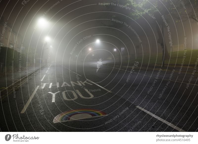 Thank you NHS rainbow painted on glossop road, Hallamshire hospital. Very foggy night scene, lit by street lamps. Empty road with no cars. UK symbol solitude