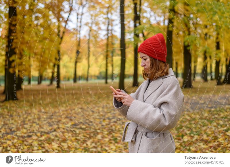 Woman using her phone at autumn park woman person lifestyle message internet communication mobile smartphone female young technology outdoor holding outside