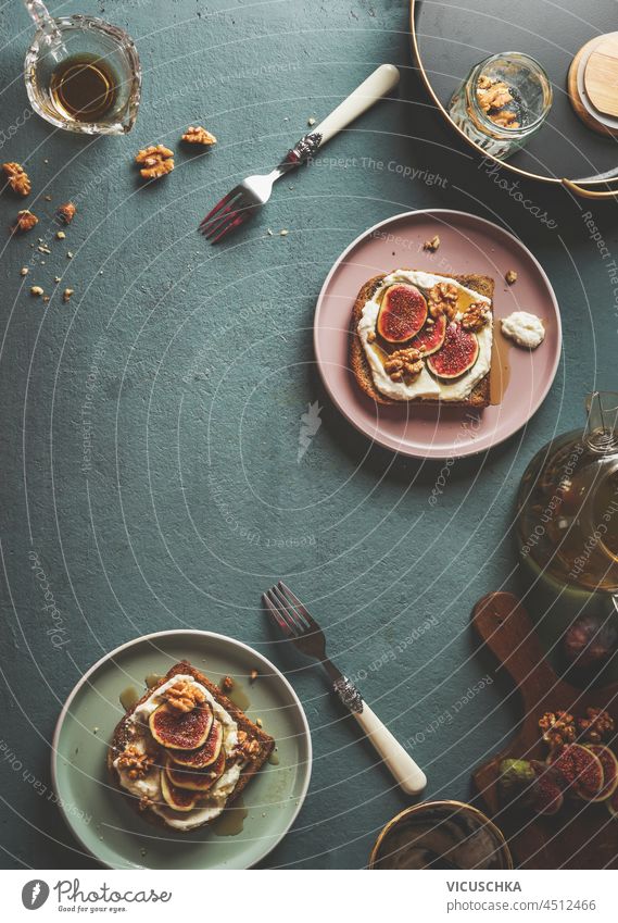 Tasty breakfast with French toast with whipped cream, sliced figs and nuts on concrete kitchen table with forks and bowls. Top view with copy space. tasty