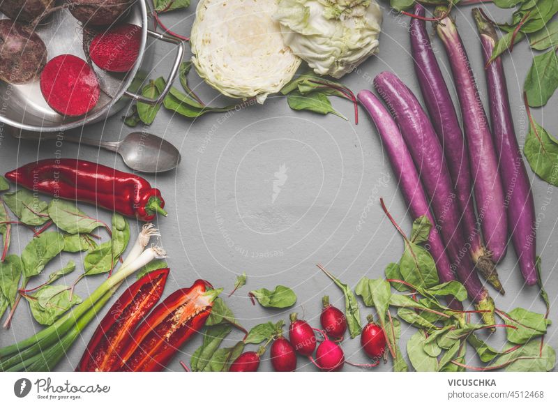 Vegetables food background with pepper, eggplant, radish, beetroot, cabbage and spring onion on grey kitchen table. Seasonal vegetables. Frame with copy space. Top view.
