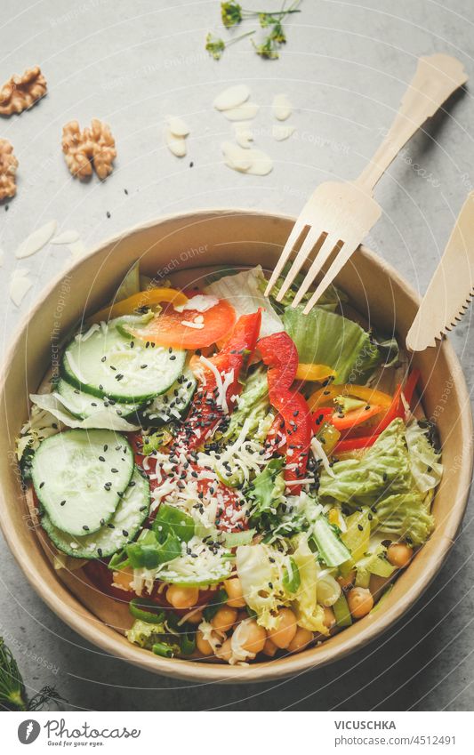 Colorful salad with vegetables in plastic free, delivery food container: cucumber, pepper, salad, chickpeas and nuts. Sustainable lifestyle with healthy vegan food. Top view.