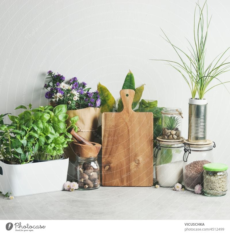 Modern kitchen with environmentally friendly food storage. Wooden cutting board, potted herbs, jars with ingredients and flowers. Front view. modern wooden