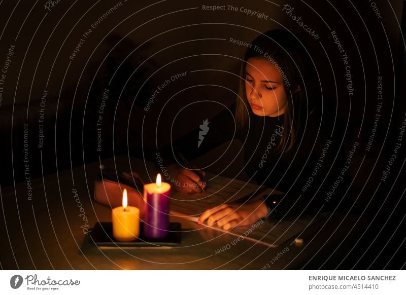 Young woman studying by candlelight. Blackout concept, power cut fire flame burn darkness glow glowing hope memorial peace burning night tranquil wax faith heat