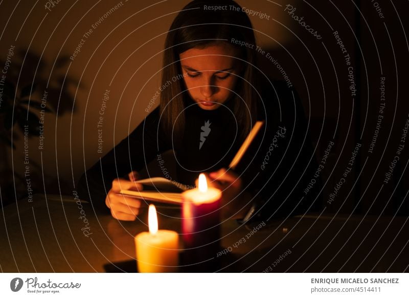Young woman reading by candlelight. Blackout concept, power cut fire flame burn darkness glow glowing hope memorial peace burning night tranquil wax faith heat