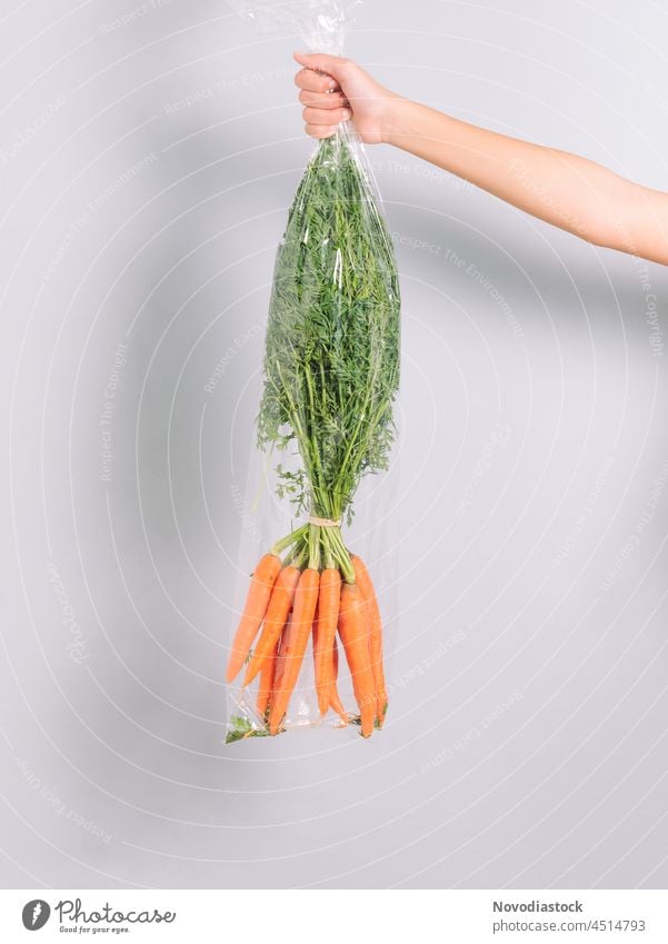hand holding a plastic bag with carrots ingredient diet food colorful isolated salad nutrition delicious fresh bunch vegetarian agriculture carotene closeup