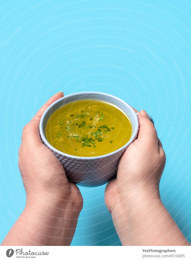 Chicken soup mug in woman hands on a blue background. beverage boiled bowl broth chicken chicken soup close-up color comfort cooked copy space cuisine cut out