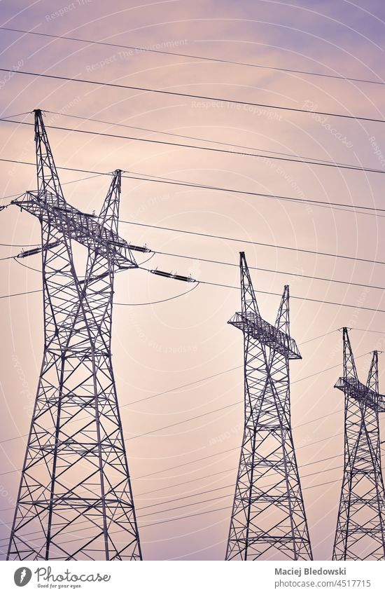 View of high voltage transmission towers against the sky, color toning applied. energy electricity industry power cable line wire technology supply industrial