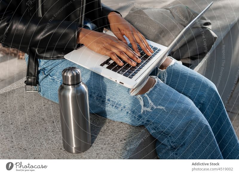 Anonymous black woman typing on laptop browsing street online freelance work notebook modern netbook gadget computer portable internet african american