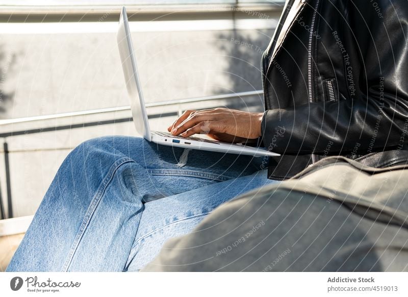 Anonymous black woman typing on laptop browsing street online freelance work notebook modern netbook gadget computer portable internet african american