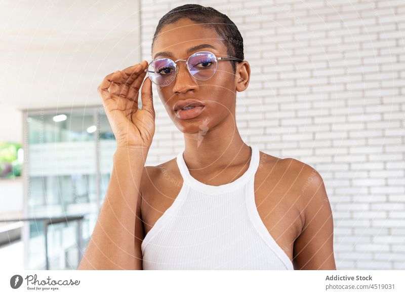 Attractive black woman near brick wall street style trendy outfit attire feminine garment eyeglasses african american female lady modern short hair appearance