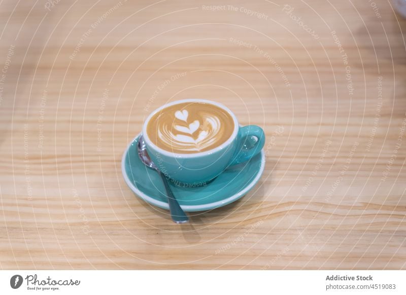 Cup of latte on plate coffee latte art cup serve cafe caffeine hot drink beverage foam teaspoon aroma cafeteria delicious fresh wooden table tasty mug froth