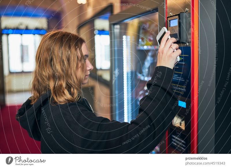 Woman paying for product at vending machine using smartphone buying contactless payment goods consumer wireless woman technology person money automatic