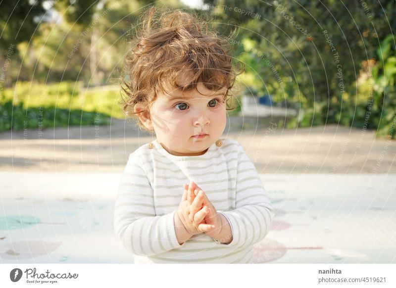 Natural portrait of a one year cute baby curly outdoors real adorable sunny day park nature natural toddler kid child babyhood childhood comfort candid calm
