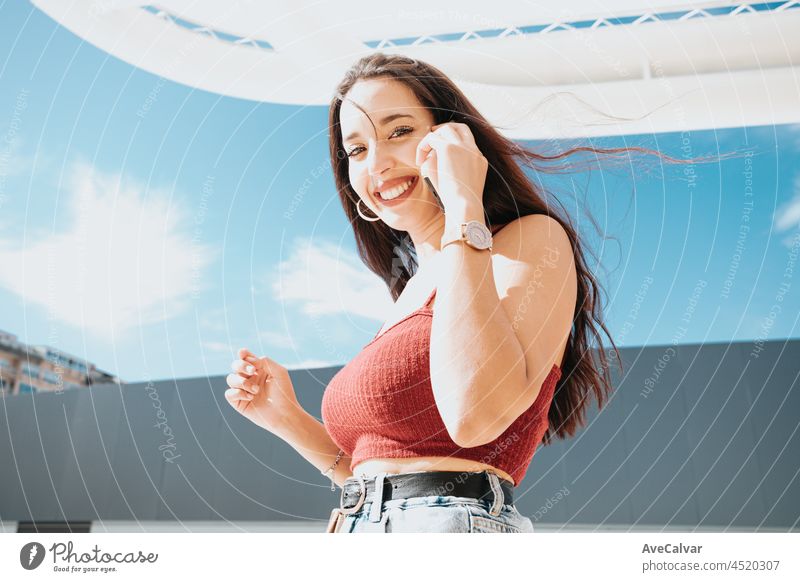 Young arab woman doing a call while holding shopping bags, shopping day, modern outfit styling, smiling to camera during a sunny day mobile phone buying african