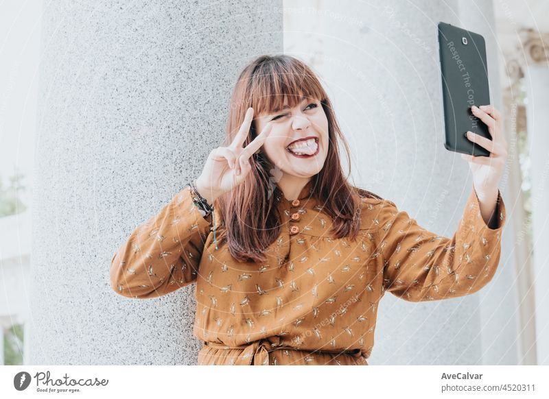 Young hipster woman on an autumnal dress taking a selfie, while making a video call, hipster happy day, freedom and liberty concepts, ginger woman, social network style, copy space
