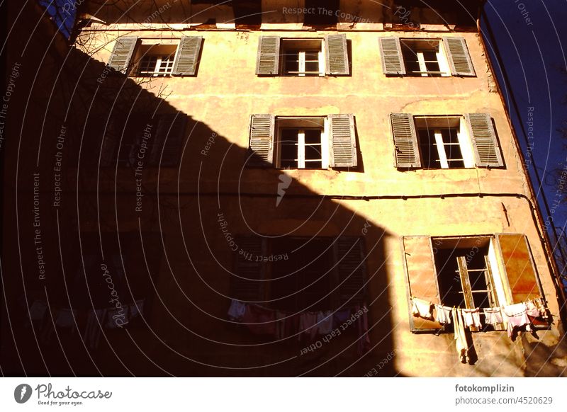old french house front with much shadow and sun contrast and clothesline at window House front Laundry Sun Window everyday life Life suitable for everyday use